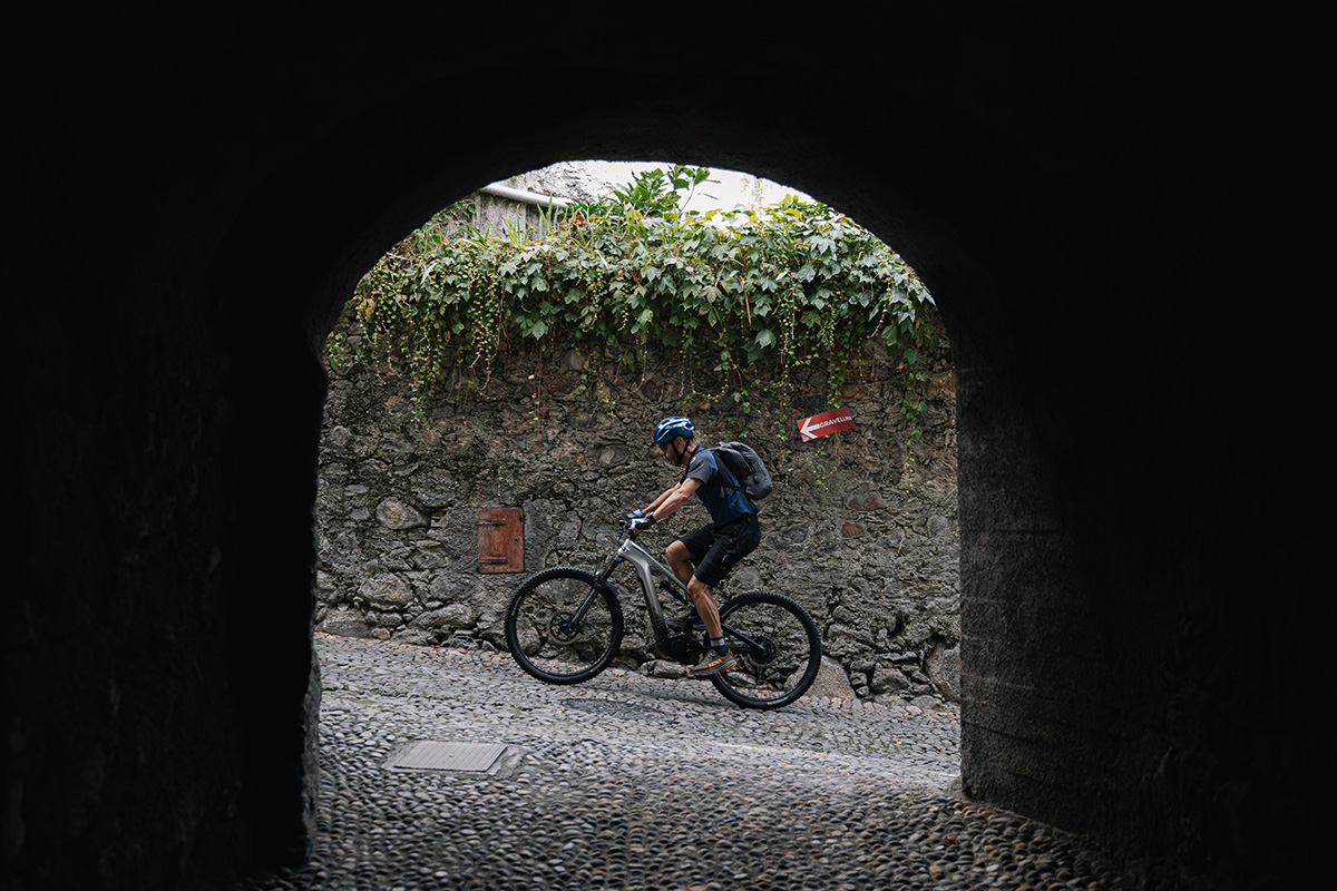 Vista di una Strada Antica con Ciclista in e-Bike da un Portone Storico