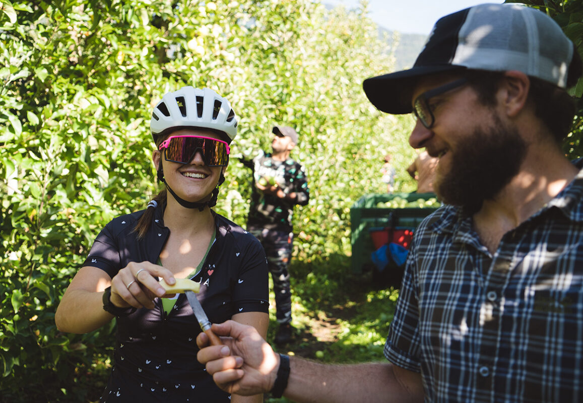 APPLE ORCHARDS BY E-BIKE Gravellina Ciclista in e-MTB mangia una Mela in Valtellina